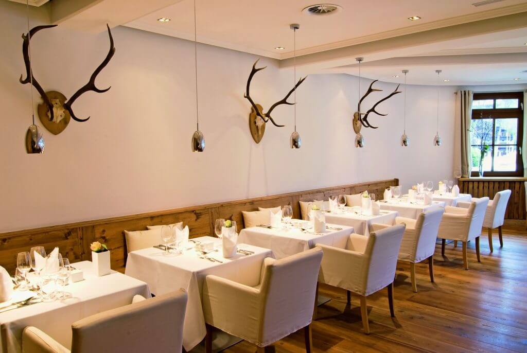 Restaurant mit hell gedeckten Tischen und Geweihdeko an der Wand